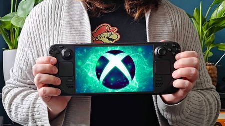 Phil Hayton holding Steam Deck OLED with Xbox logo on screen and plants in backdrop.