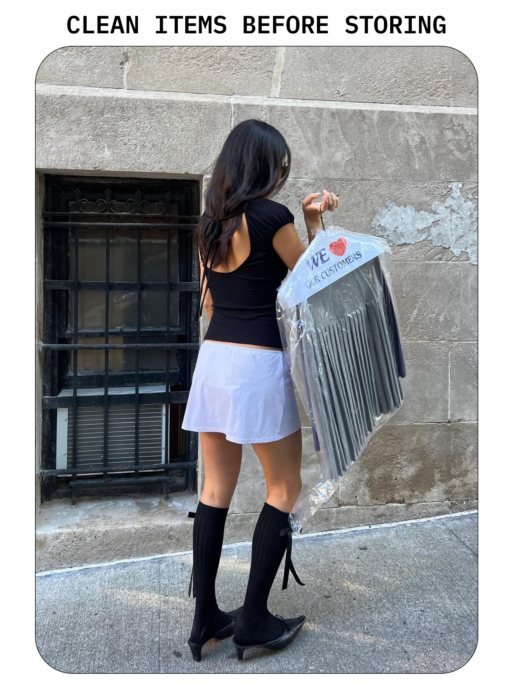 Woman holding bag of dry-cleaned clothing.