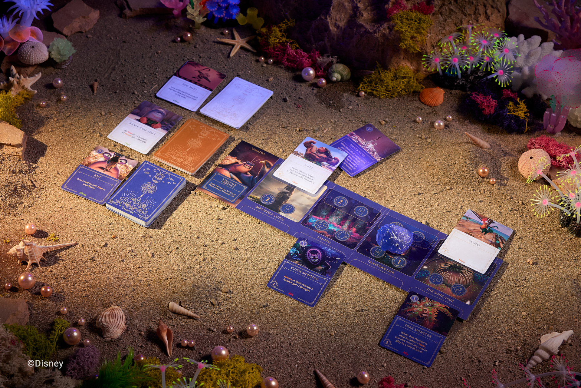 Disney Villainous: Treacherous Tides cards, tokens, and pieces on themed background with sand, shells, pearls, and coral