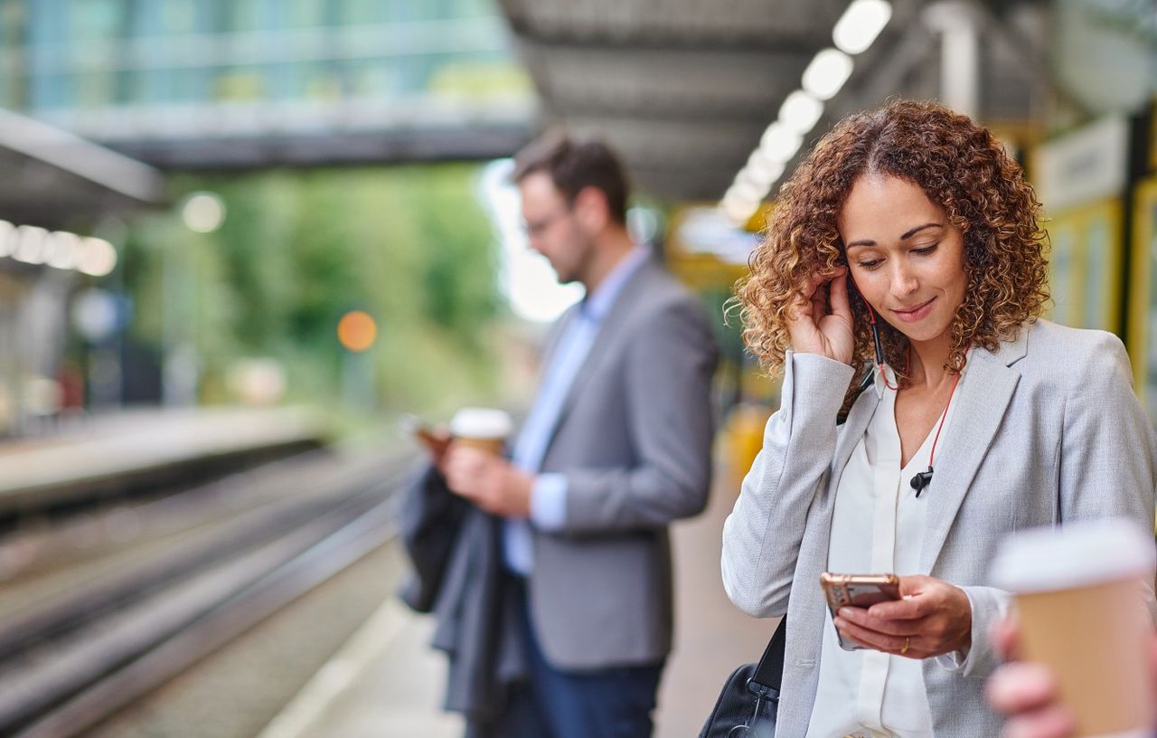 A young woman waits for the commuter train while on her mobile phone. 