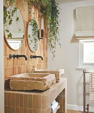 bathroom with tiled vanity and rough marble countertop sinks