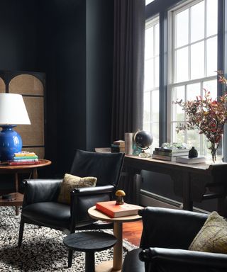 living room with black walls, black armchairs in front of large window