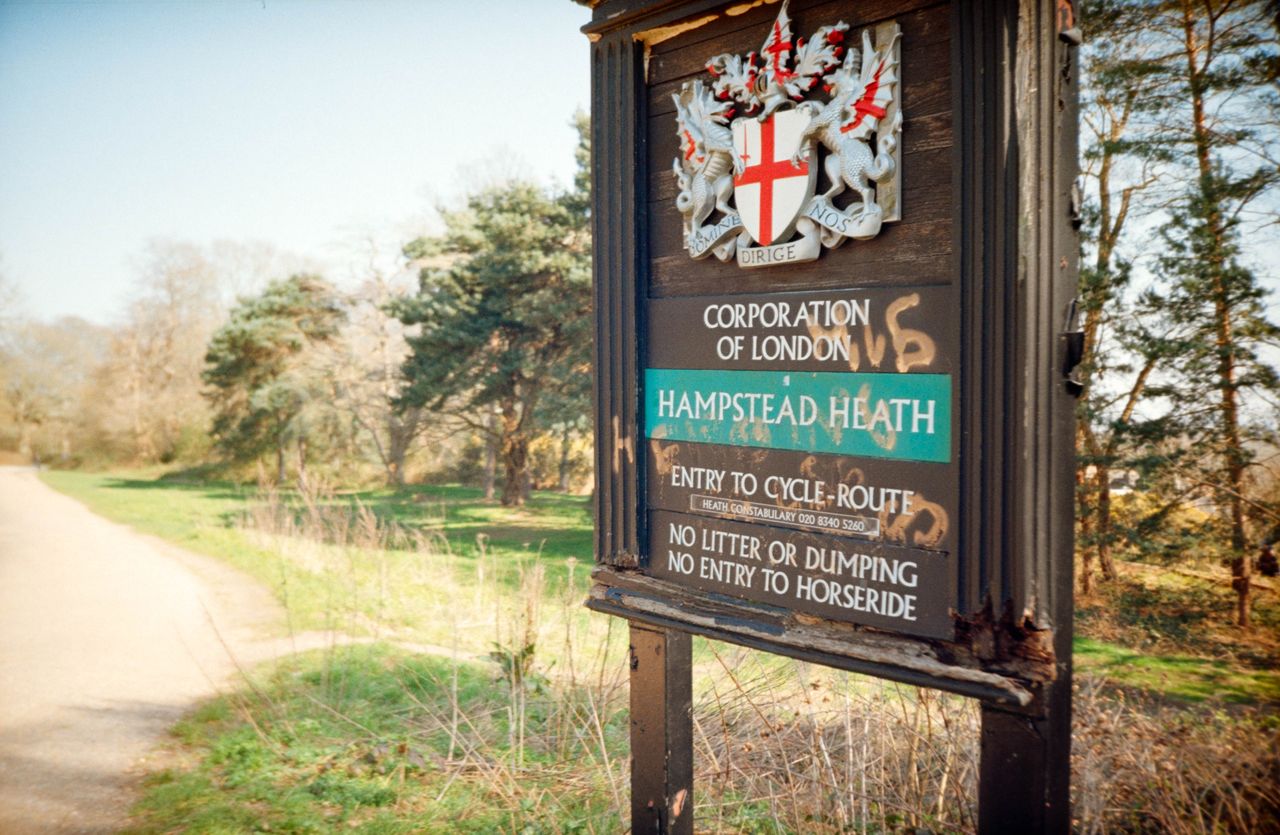 Scanned and digitized film image, using Valoi Easy 35 Pro V2 and Negative Lab Pro Lightroom plugin. Image shows a sign for Hampstead Heath covered in grafitti