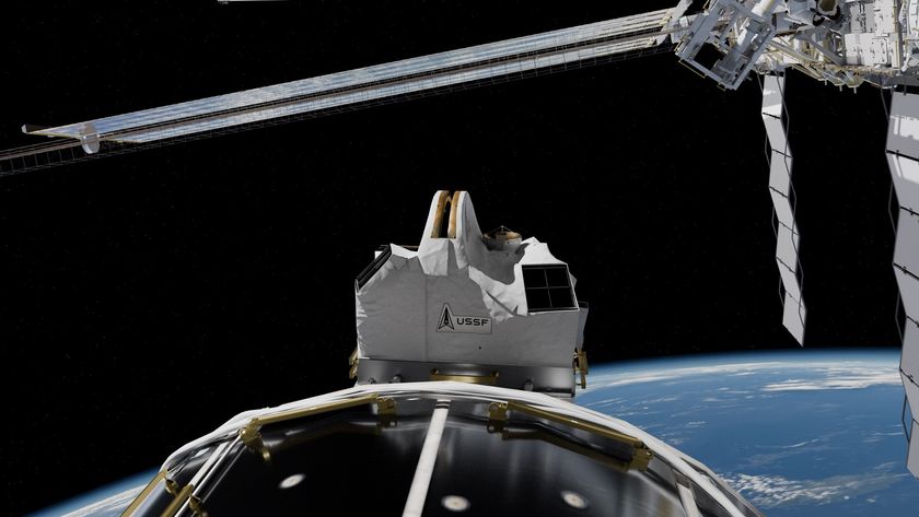 a white rectangular box-like structure on the outside of a large white cylinder above earth