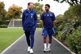 England Manager Gareth Southgate and Raheem Sterling of England walk to a press conference following a training session at Tottenham Hotspur Training Centre on September 25, 2022 in Enfield, England