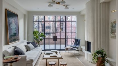 A neutral white living room with curved fluted plaster fireplace