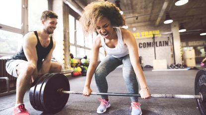 How often should you lift weights? Image shows young woman lifting barbell