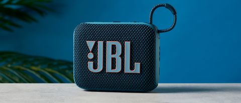 A photo of the JBL Go 4 in blue on a concrete surface against a blue wall.