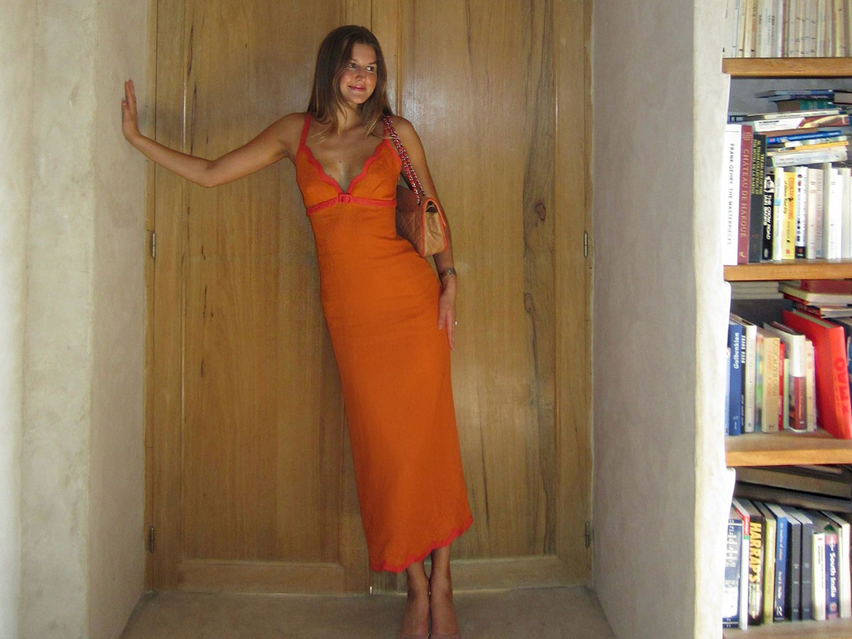 @styledsara wearing an orange Reformation maxi dress.
