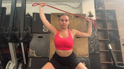 Woman doing a squat and press with a resistance band.