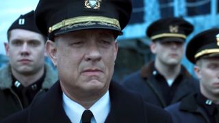 Tom Hanks as Commander Ernie Krause looking sad in a group of soldiers during the Apple TV movie Greyhound.