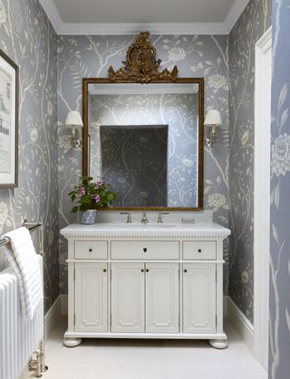 Blue rose pattern wallpaper, white cabinet with sink and bronze mirror