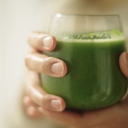 A woman holding a green smoothie