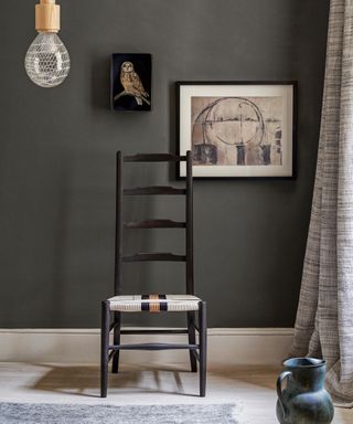 A Scandi inspired dark gray-black living room with black wooden chair and artwork.