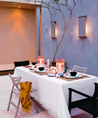 Patio with lighting on the wall and candles on a table set for dinner