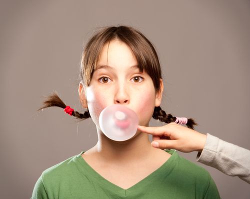 A girl blows bubbles with chewing gum