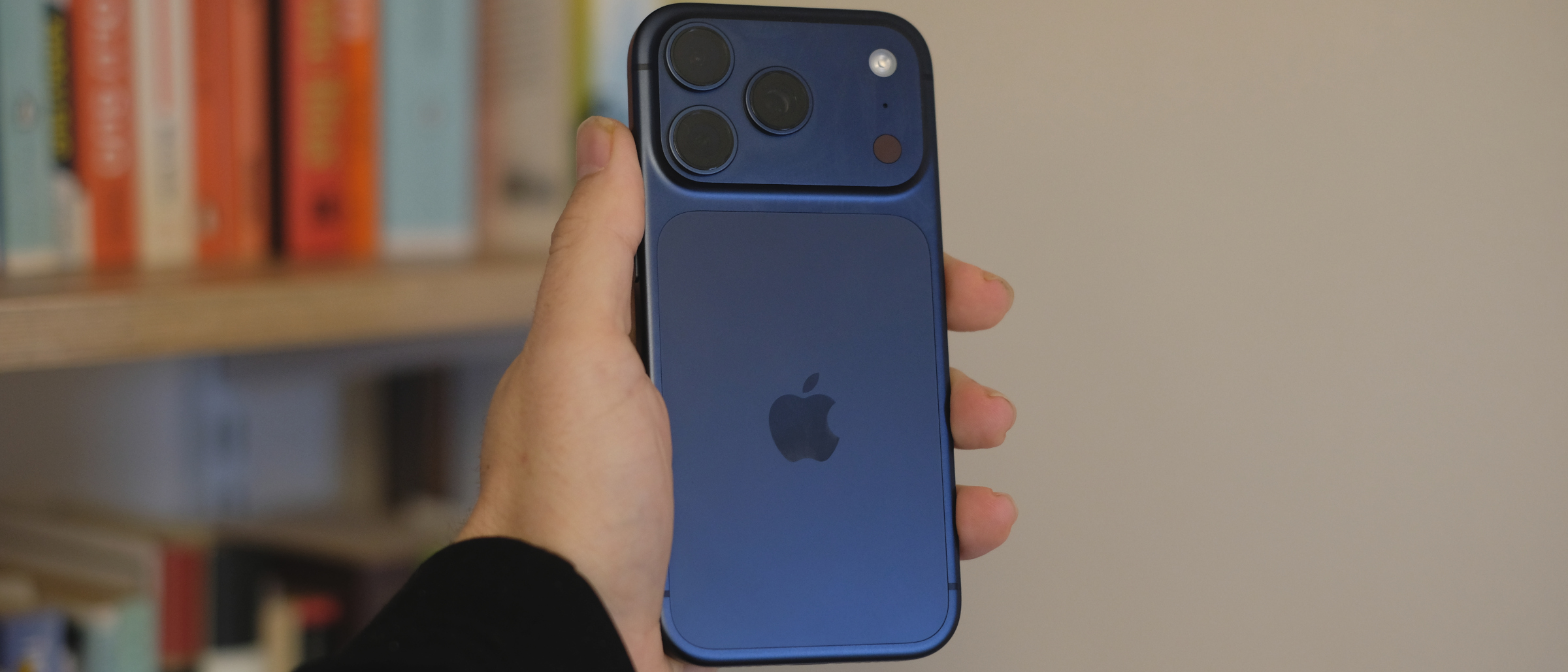 Hand holding iPhone 17 Pro, rear view with camera array visible