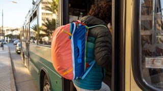 Man entering bus wearing a Cotopaxi backpack