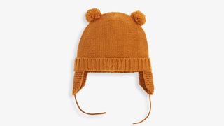 A gold-coloured knitted baby hat on a white background