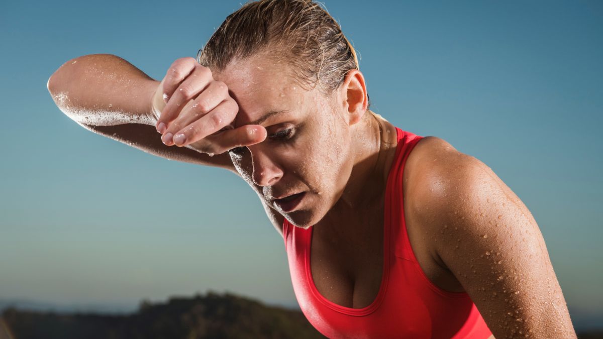 Woman wiping sweat from forehead