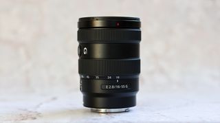 Sony E 16-55mm f/2.8 G Lens standing upright against a marbled backdrop