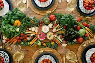 table centerpiece with fresh vegetables, rattan chargers and dips