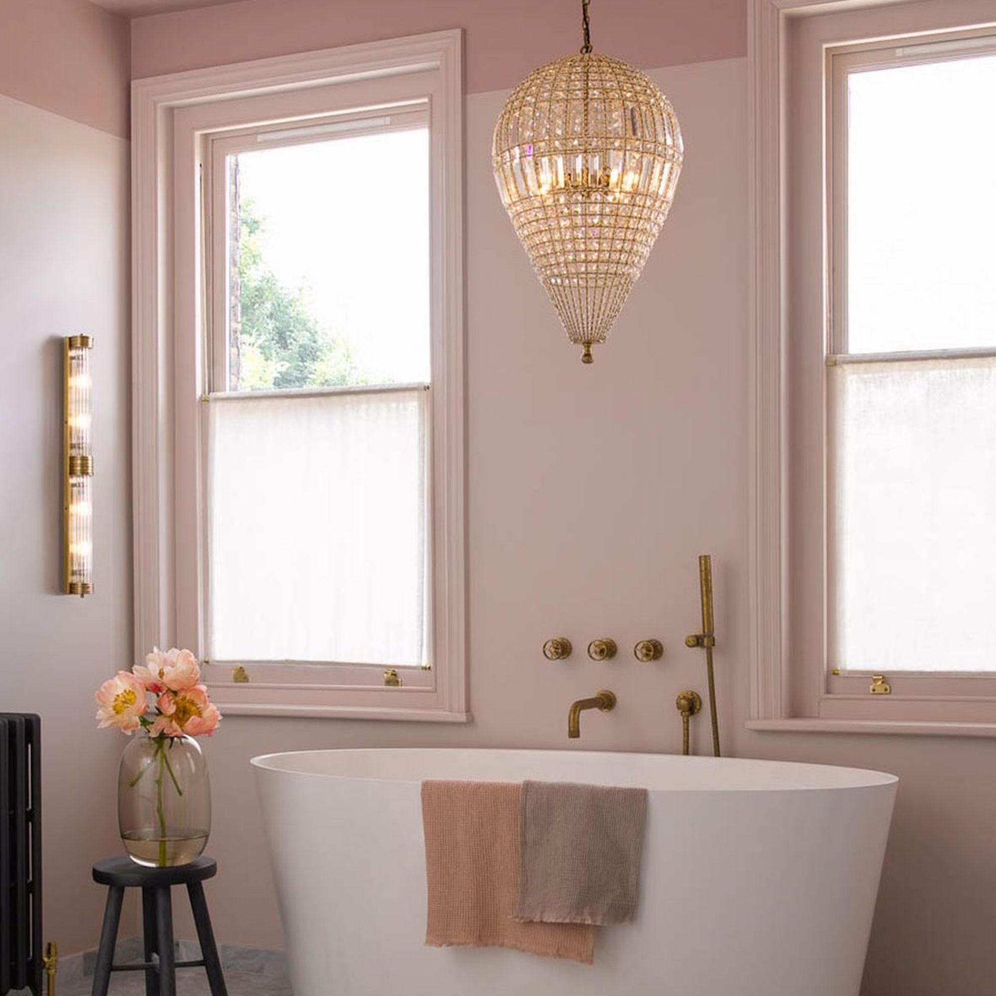 pink bathroom with white bath and lit chandelier above