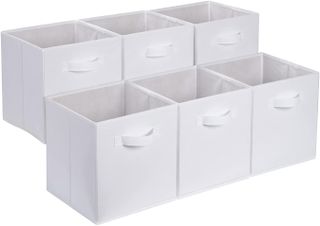 A set of six white material storage baskets