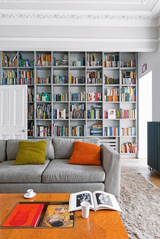 White living room with gray built in bookshelves, and gray sofa with wooden coffee table