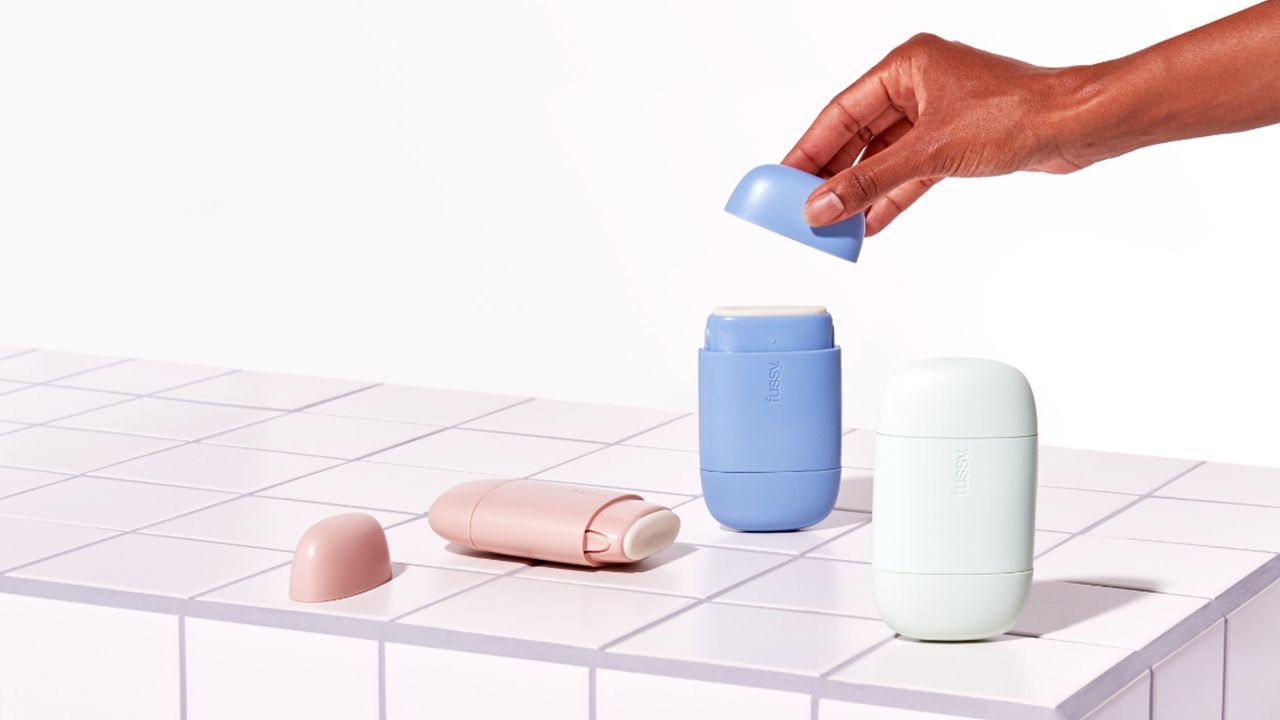 Fussy deodorant review image showing a hand lifting the lid on fussy deodorant on a tiled surface 