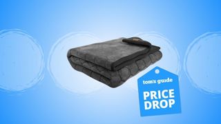 The image shows a folded grey blanket against a blue back ground with a Tom's Guide 'Price Drop' badge laid over the top