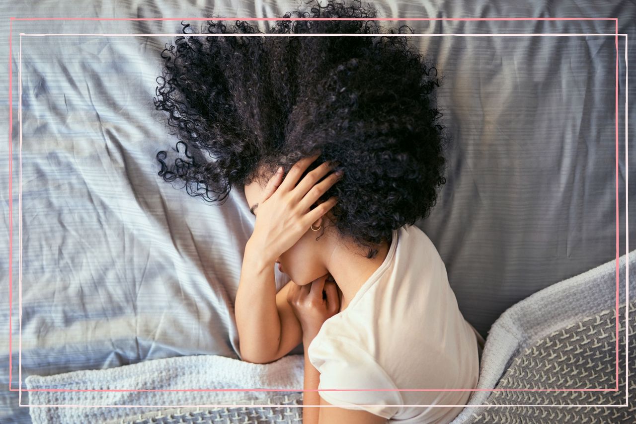 A woman suffering from Tinnitus in pregnancy lies in bed with her arm covering her face and her hand over her ear