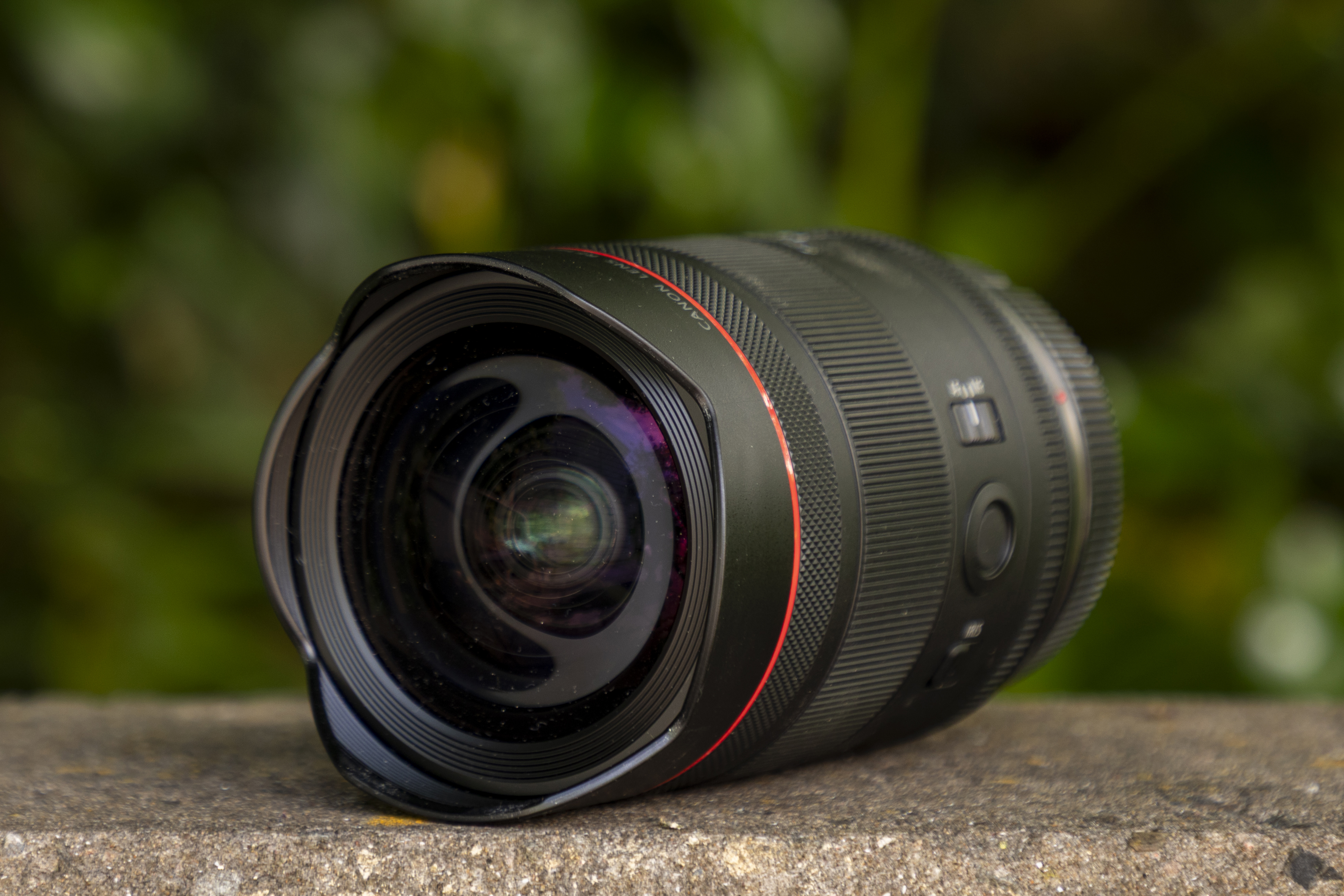 Canon RF 14mm f/1.4L VCM lens on wall with greenery behind