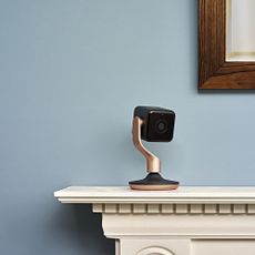 Hive View indoor security camera on a mantlepiece with a blue wall behind it