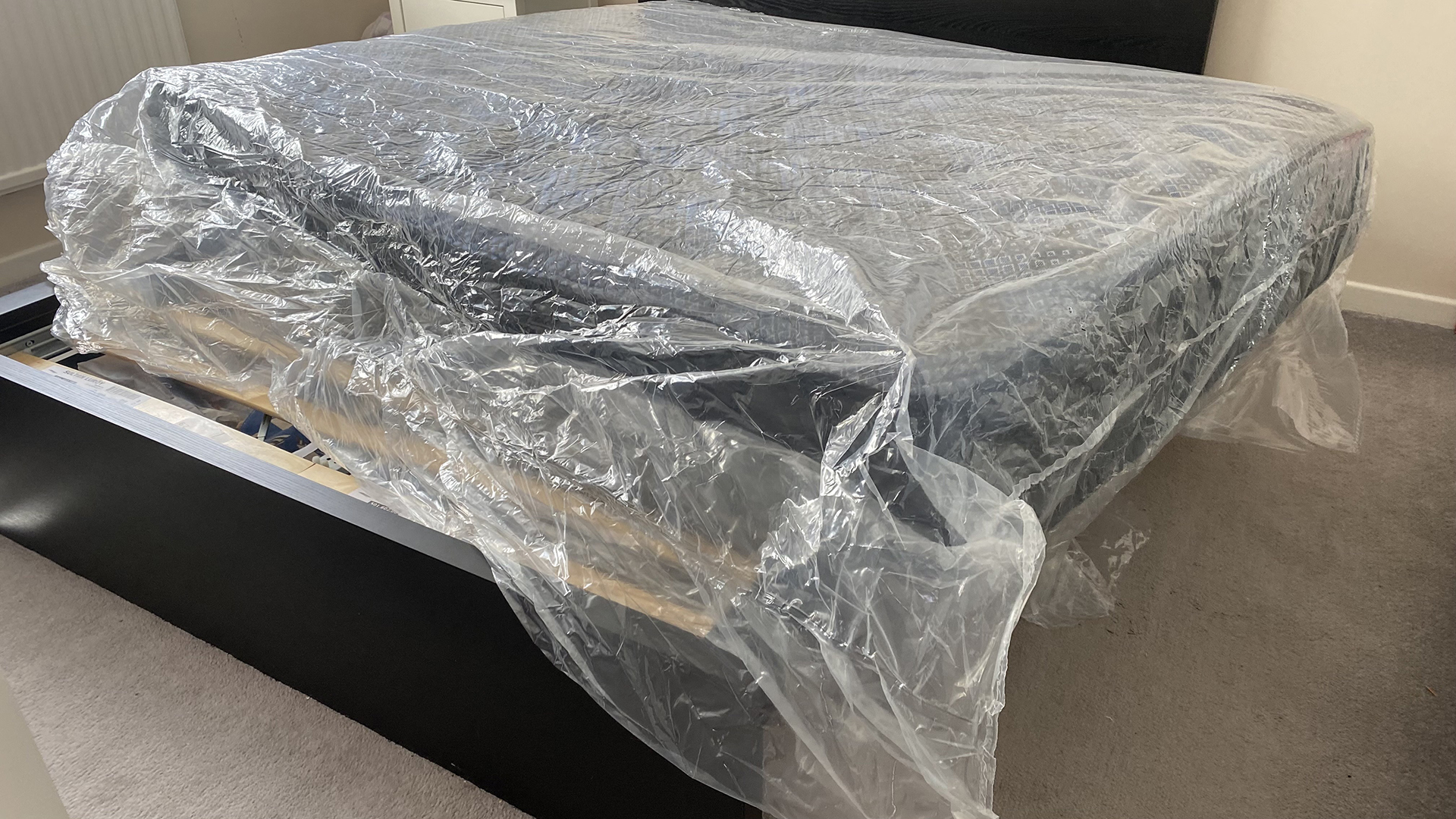 The Dreamstage Value Quilted Hybrid mattress unrolled but still in its packaging, on a bed frame in our tester's bedroom