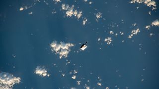 a white bag floats in space above Earth