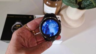 Huawei Watch GT 5 Pro holdes oppe med et bilde av en astronaut som urskive.