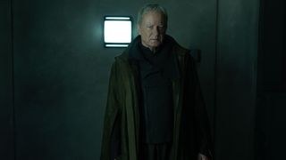 Luthen Rael standing in a room with a wall light on behind him in Andor season 2