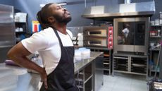 chef in kitchen holds sore back after being on his feet all day