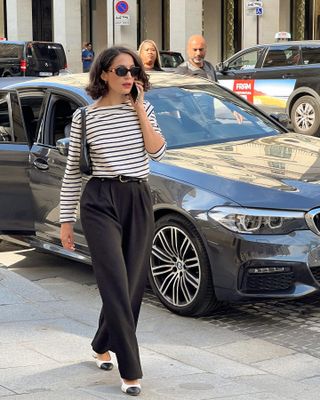 @melodiebance walking on the phone in Paris with a striped top and a curly bob