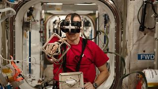 NASA astronaut Bob Hines wearing VR goggles and hand equipment on the space station.