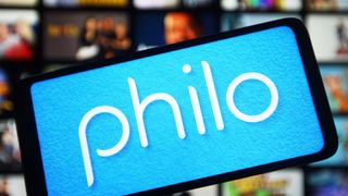 The Philo app shown on a phone in front of a TV