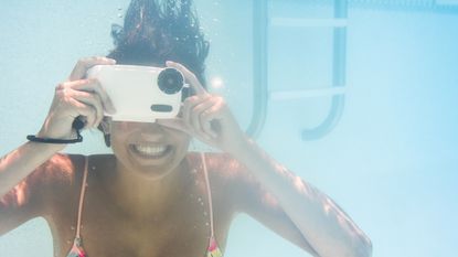 Woman underwater in a swimming pool taking a picture with an underwater camera