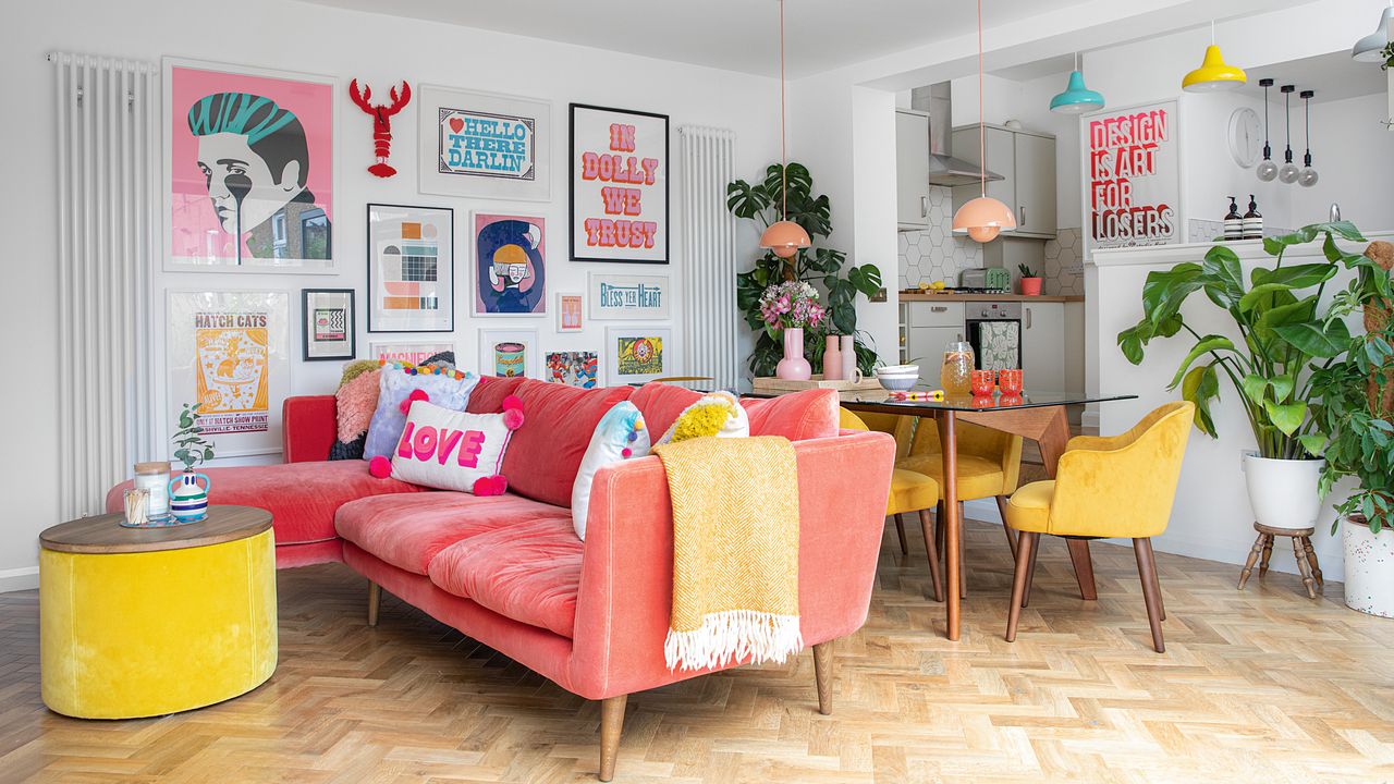 Colourful living room with parquet floor, pink sofa, yellow dining chairs and gallery wall