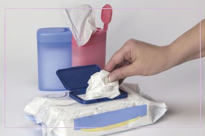 An open pack of wet wipes with a hand pulling one from the top