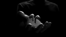 Apple AirPods Pro 2 suspended above a hand, on black background