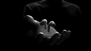 Apple AirPods Pro 2 suspended above a hand, on black background