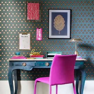 retro graphic blue and gold wallpaper on wall with a fuschia pink chair