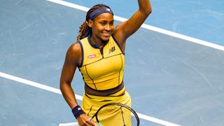 Coco Gauff of the United States, wearing a bright yellow New Balance tennis outfit, standing on a light blue tennis court, ahead of the Gauff vs Sabalenka Australia Open semi-final 2024. 