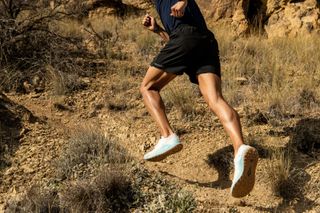 Athlete running on uneven terrain wearing Brooks' Catamount trail running shoes